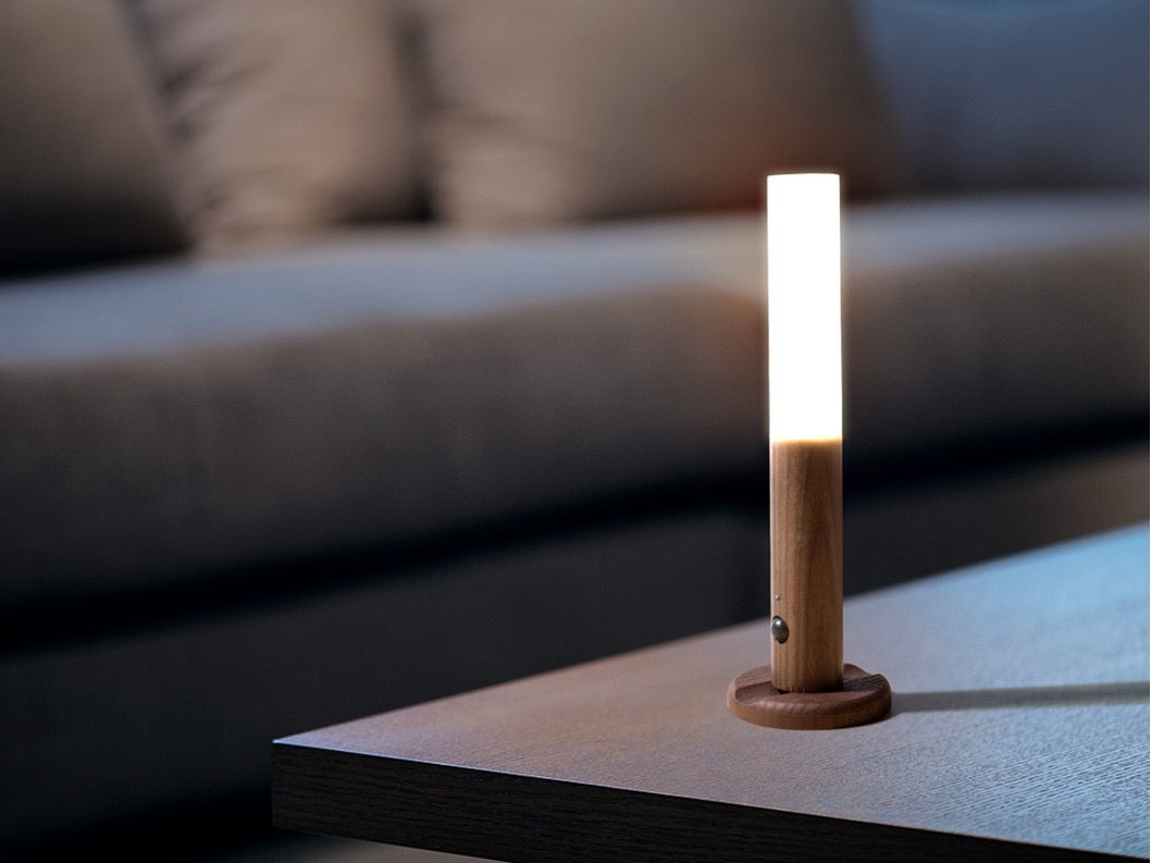 Wooden lamp with a white light bulb on a table, blurred sofa in the background