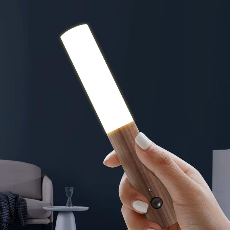Hand holding a wooden light bar with a dark background